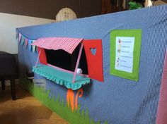 a blue tent with a red and green awning on it's side in the middle of a room