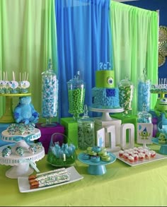 a table topped with lots of different types of desserts and candies covered in blue and green icing