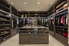 a walk in closet with lots of shoes and clothes on the shelves next to it