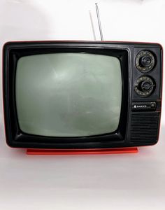 an old tv sitting on top of a red stand