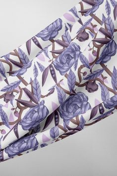 a purple and white floral print fabric with leaves on it's side, laying flat