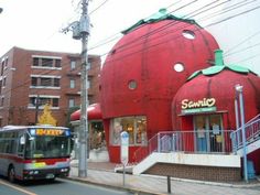 a bus driving past a giant strawberry shaped building