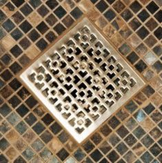 a drain in the middle of a tiled floor with grouting on it's sides