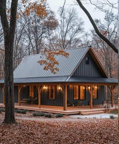 a small cabin in the woods with lots of leaves on the ground and trees around it