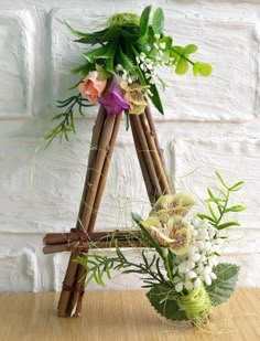 an arrangement of flowers and greenery on a wooden stand