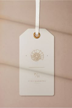 a white tag hanging from the side of a wall with a gold ring on it