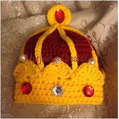 a crocheted hat with red and yellow beads on it, sitting on top of a white fabric