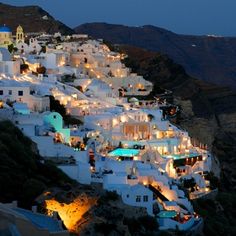 the white houses are lit up at night in the mountainside area, with lights shining on them