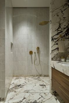 a bathroom with marble walls and flooring next to a walk - in shower area