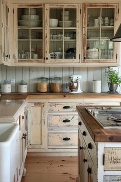 an old fashioned kitchen with white cabinets and wood flooring on the counter top,