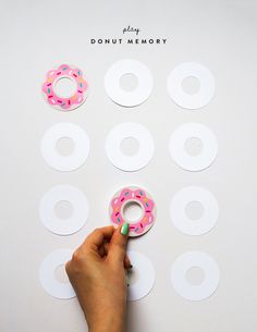 a person holding a doughnut in front of several donuts cut out from paper