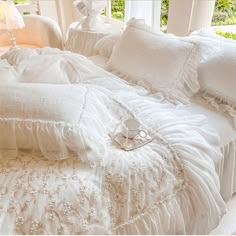 a bed with white ruffled sheets and pillows