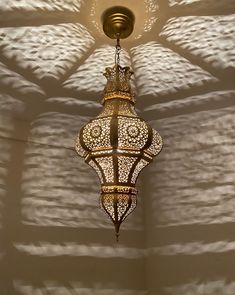 a chandelier hanging from the ceiling in a room with white walls and shadows