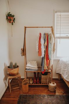 a clothes rack in a bedroom next to a bed with shoes and blankets on it