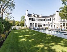 a large white house with a swimming pool in the front yard and landscaping around it