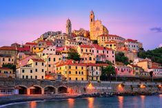 an old town on top of a hill next to the ocean at sunset or dawn