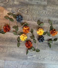 flowers are arranged on the wooden floor with green leaves and brown berries in the center