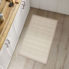 a white rug on the floor in a kitchen next to some drawers and utensils