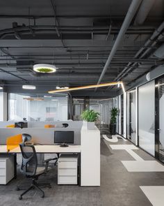 an office cubicle with desks, chairs and plant in the middle of it