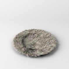 an animal fur covered dish on a white surface