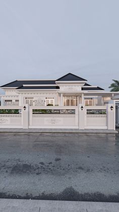 a large white house with black roof and fenced in area next to the street