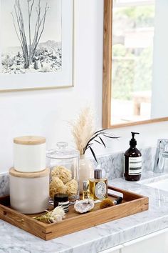 a bathroom counter with soaps, candles and other items on the tray in front of it