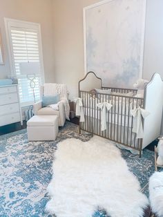 a baby's room is decorated in white and blue colors with sheepskin rugs on the floor