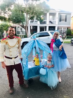 a man and woman in costumes standing next to a baby carriage with two children dressed as princesses