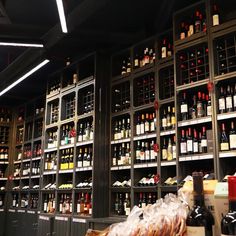 bottles of wine are lined up on the wall in this room with shelves full of bottles