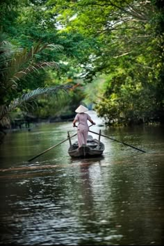 a person on a small boat in the middle of a body of water with trees