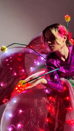 a woman dressed as a fairy with lights on her body and wings, holding a wand