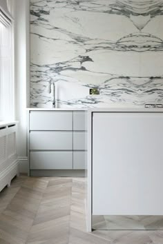 an instagramted photo of a bathroom with marble wallpaper and white cabinetry