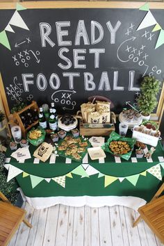 a football themed party with snacks and desserts on a table in front of a chalkboard