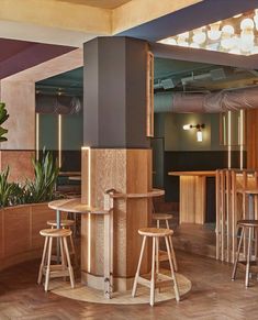 the interior of a restaurant with wooden tables and stools, potted plants on the wall