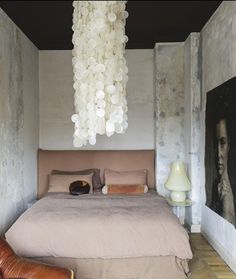 a bedroom with a bed, chair and chandelier hanging from it's ceiling