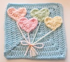 a crocheted square with three hearts on it