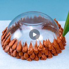 a glass bowl filled with lots of brown stuff next to a green leaf on top of a table