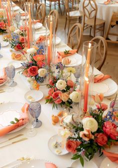 the table is set with orange, pink and white flowers