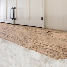 a kitchen counter top made out of wood and white cupboards with doors on each side