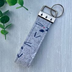 a keychain with a cat design on it and a plant in the background