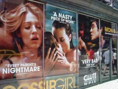 a movie poster on the side of a building in front of a window with advertisements