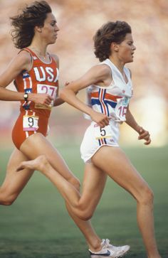 two women are running on the field during a race