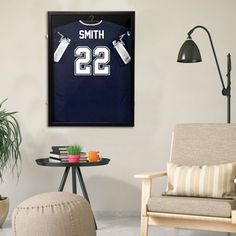 a living room filled with furniture and a framed football jersey on the wall next to a chair