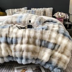 a bed with blue and white fur on it next to a magazine that is laying on the floor