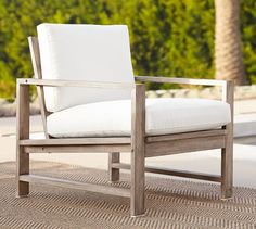 a white chair sitting on top of a rug next to a pool and palm trees