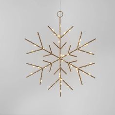 a snowflake ornament with lights hanging from it's side on a white wall