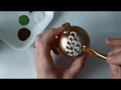 a person is decorating a christmas ornament with gold and white icing