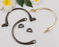 three metal hooks and two flowers on a white surface