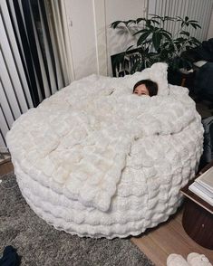 a woman is laying in a giant bed made out of blankets and pillows on the floor