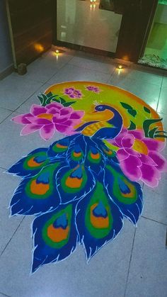 a colorful peacock design on the floor with candles